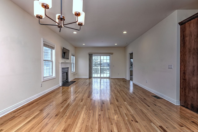 unfurnished living room with light hardwood / wood-style flooring and an inviting chandelier