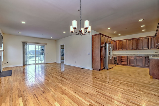 kitchen featuring light stone countertops, decorative light fixtures, light hardwood / wood-style flooring, a notable chandelier, and stainless steel fridge with ice dispenser