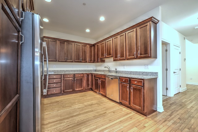 kitchen featuring light stone counters, sink, stainless steel appliances, and light wood-type flooring