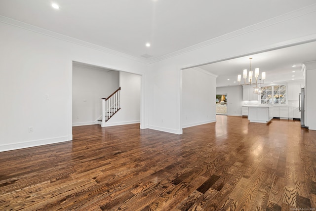 unfurnished living room featuring dark hardwood / wood-style floors, crown molding, and an inviting chandelier