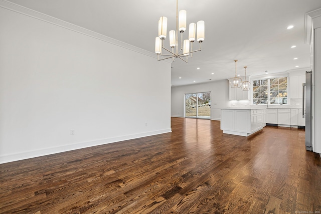 unfurnished living room featuring dark wood-type flooring, plenty of natural light, ornamental molding, and an inviting chandelier