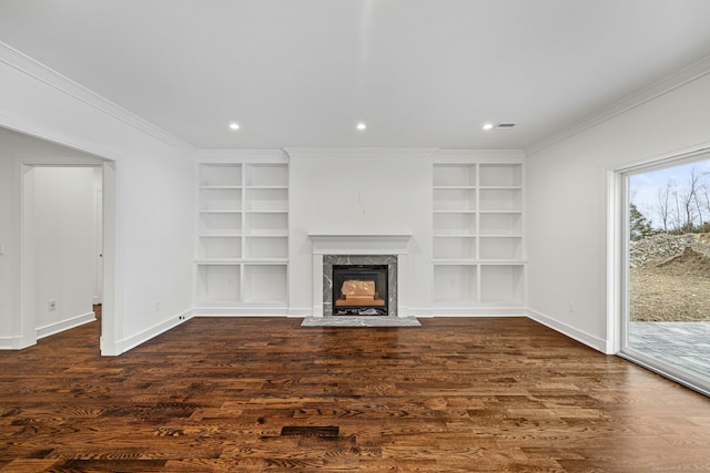 unfurnished living room featuring built in shelves, crown molding, a fireplace, and dark wood-type flooring