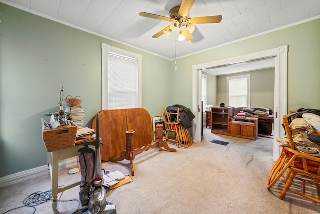 interior space with light carpet, baseboards, ornamental molding, and a ceiling fan