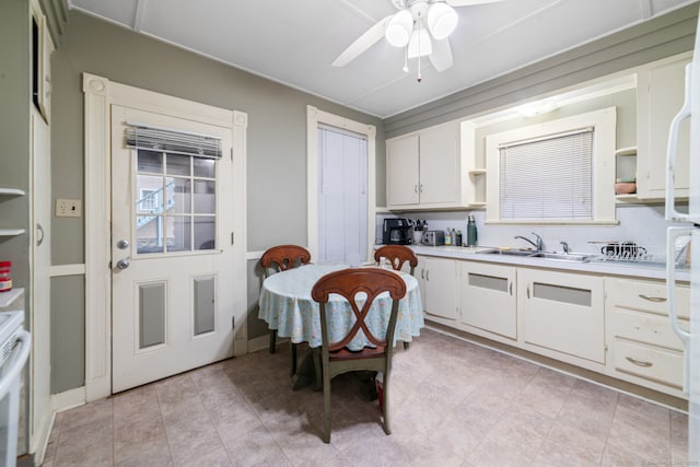 kitchen with white cabinets, ceiling fan, range, and sink