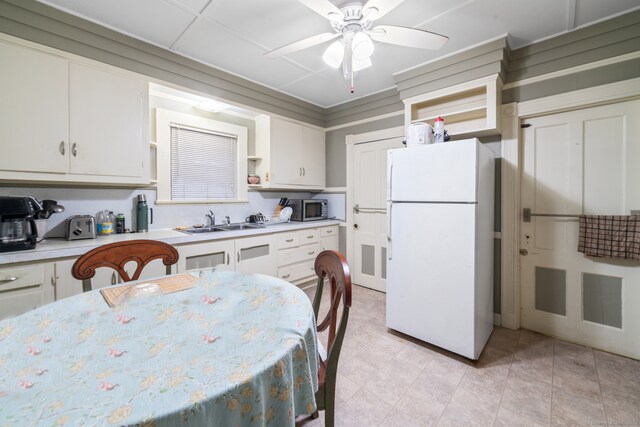 kitchen featuring white cabinets, ceiling fan, white fridge, and sink