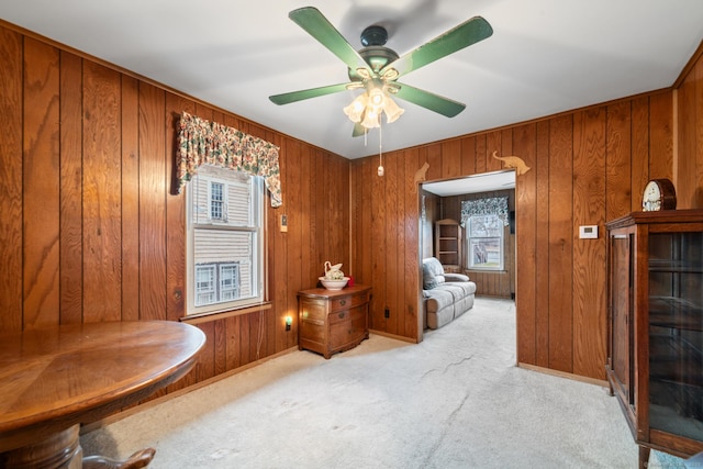 living area featuring light colored carpet, ceiling fan, and wood walls