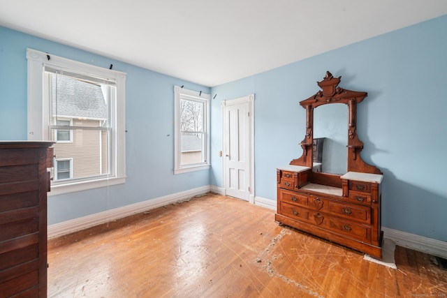 bedroom with light wood-type flooring, multiple windows, and baseboards