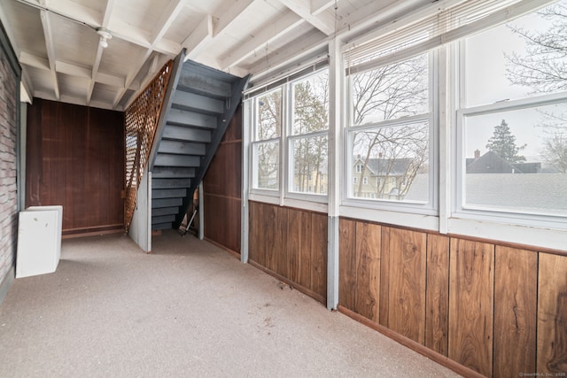 interior space with stairway, light carpet, and wooden walls