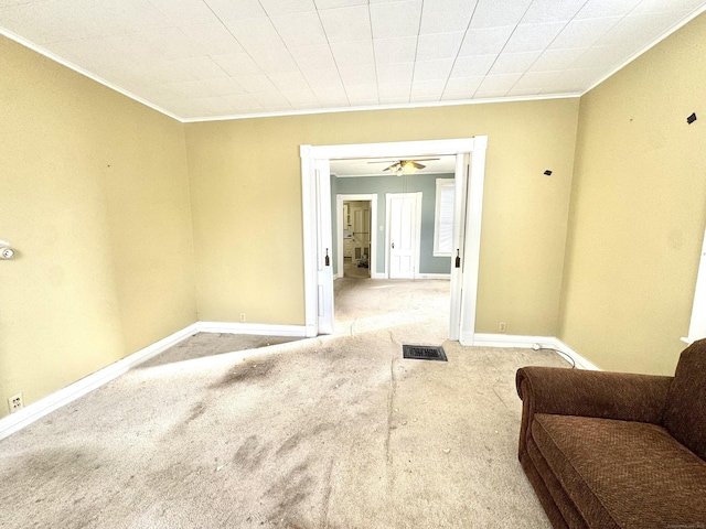 interior space with ornamental molding, light colored carpet, visible vents, and baseboards