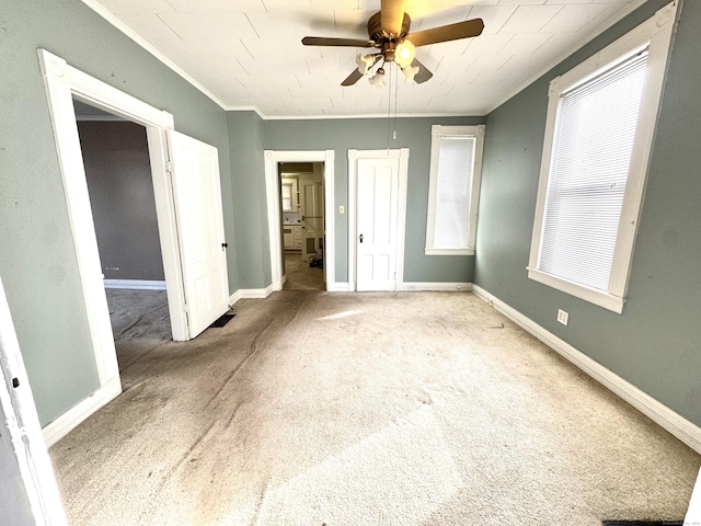 spare room with light colored carpet, crown molding, baseboards, and ceiling fan