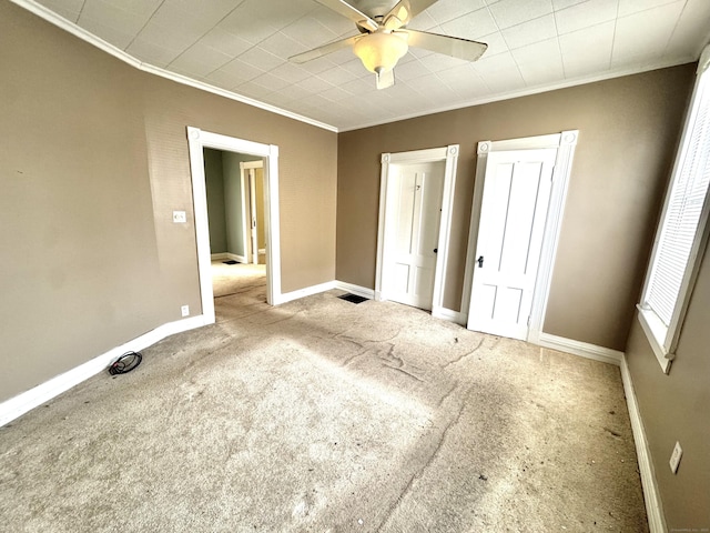 unfurnished bedroom featuring carpet floors, a ceiling fan, baseboards, and crown molding