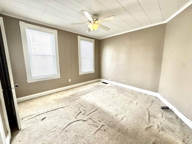 spare room with ornamental molding, carpet flooring, a ceiling fan, and baseboards