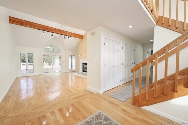 unfurnished living room featuring a glass covered fireplace, lofted ceiling, hardwood / wood-style floors, and rail lighting