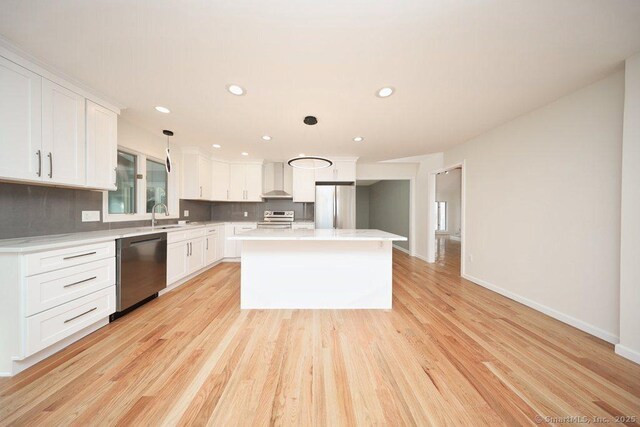 kitchen with a center island, backsplash, hanging light fixtures, white cabinetry, and stainless steel appliances