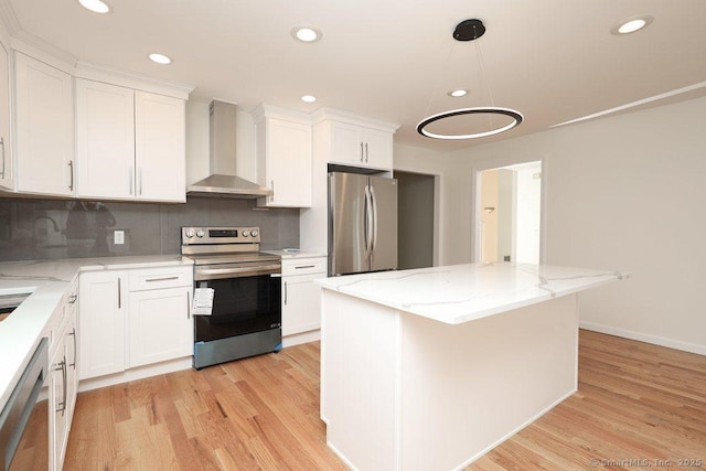 kitchen with wall chimney range hood, white cabinets, appliances with stainless steel finishes, and light wood-style flooring