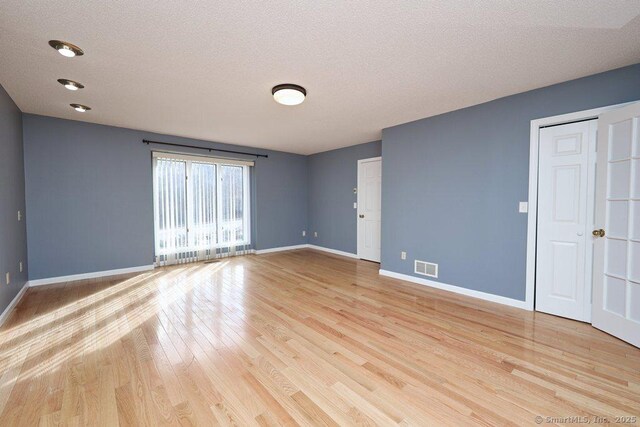 spare room featuring a textured ceiling and light hardwood / wood-style flooring