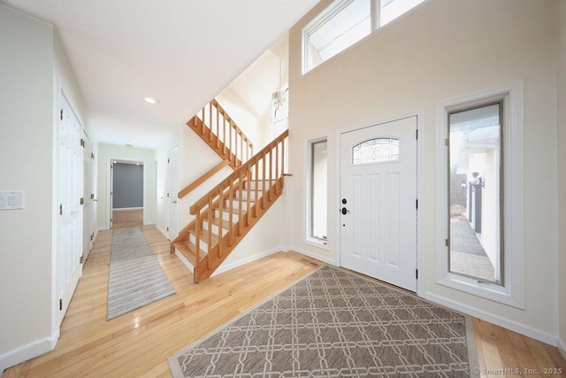 foyer entrance with recessed lighting, stairs, baseboards, and wood finished floors