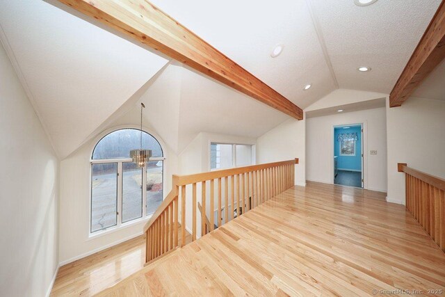 hallway with a chandelier, light hardwood / wood-style flooring, lofted ceiling with beams, and a textured ceiling