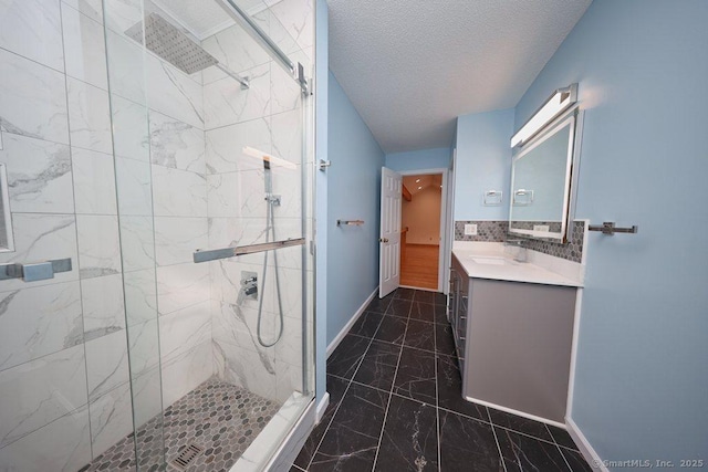 full bathroom featuring a marble finish shower, baseboards, a textured ceiling, and vanity