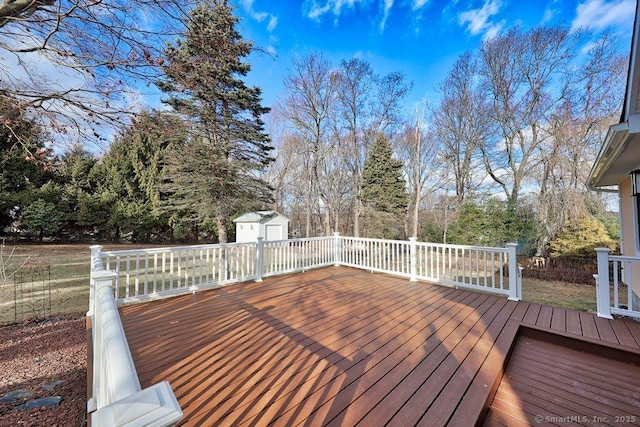 wooden deck with a storage shed, an outbuilding, and fence