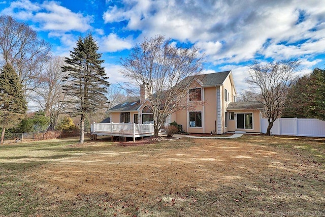 rear view of house with a lawn and a wooden deck