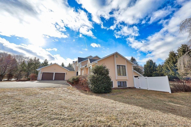 view of side of home featuring fence, stucco siding, a lawn, a garage, and a gate