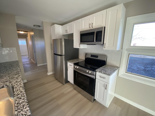 kitchen featuring decorative backsplash, stainless steel appliances, light hardwood / wood-style flooring, stone counters, and white cabinetry