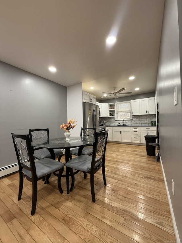 dining room featuring light wood-type flooring, ceiling fan, and sink