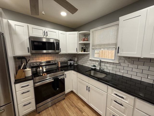 kitchen featuring white cabinets, appliances with stainless steel finishes, decorative backsplash, and sink