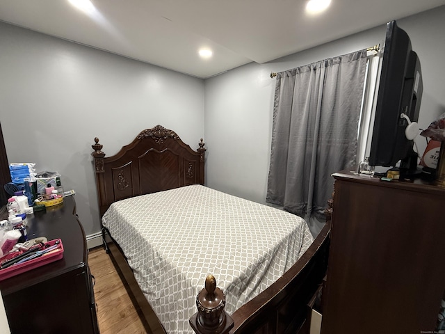 bedroom with light wood-type flooring and a baseboard radiator