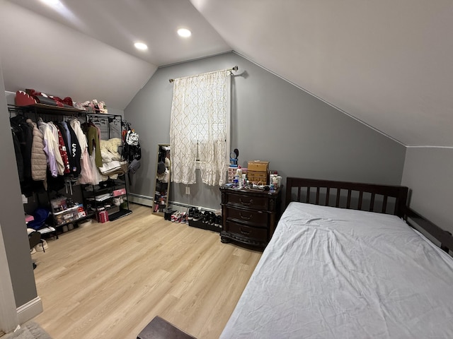 bedroom with a baseboard radiator, light hardwood / wood-style flooring, and lofted ceiling