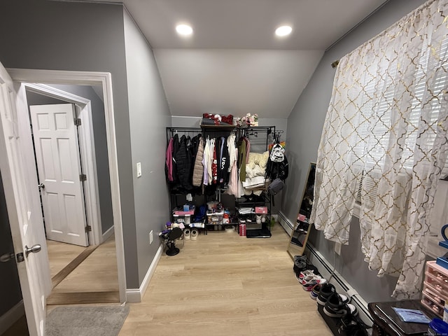 walk in closet with light hardwood / wood-style flooring, a baseboard radiator, and lofted ceiling