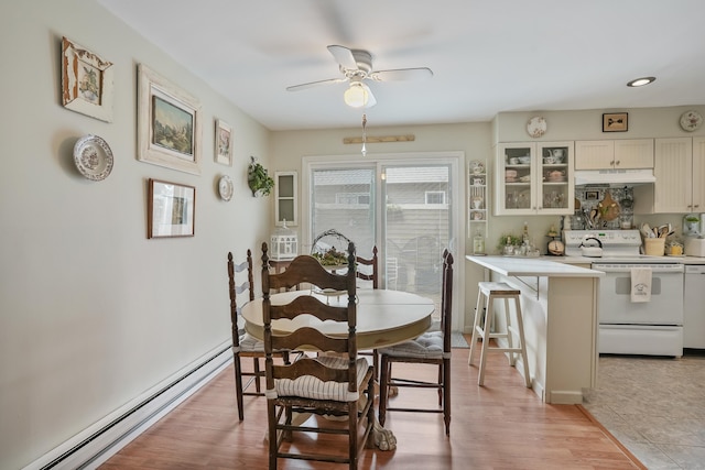 dining area with ceiling fan, a baseboard radiator, and light wood-type flooring