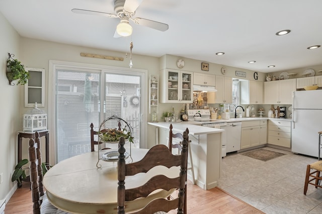 kitchen featuring ceiling fan, sink, light hardwood / wood-style flooring, kitchen peninsula, and white appliances