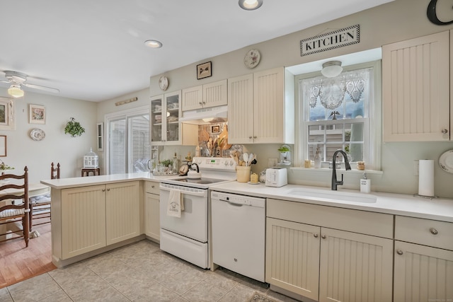 kitchen featuring stove, white dishwasher, sink, cream cabinetry, and kitchen peninsula