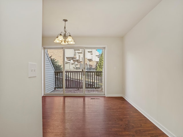 unfurnished room featuring dark hardwood / wood-style flooring and an inviting chandelier