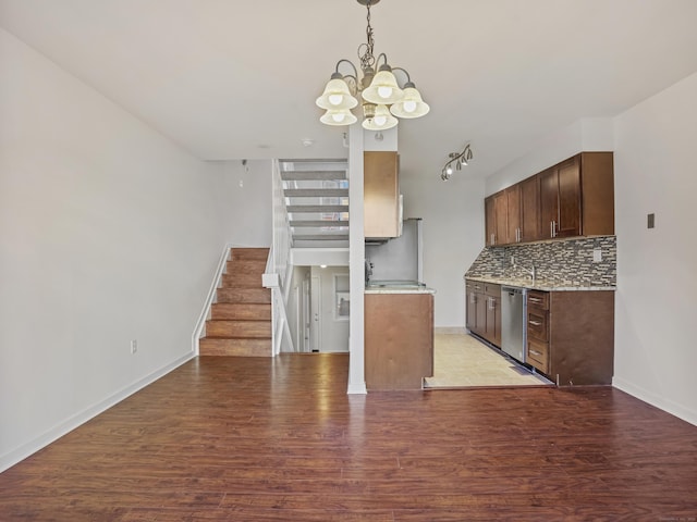 kitchen featuring stainless steel dishwasher, decorative backsplash, an inviting chandelier, and light hardwood / wood-style flooring