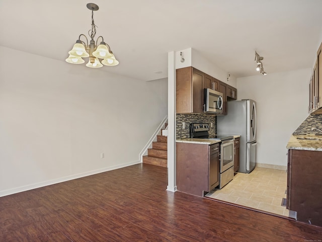 kitchen featuring backsplash, light stone counters, stainless steel appliances, and light hardwood / wood-style floors