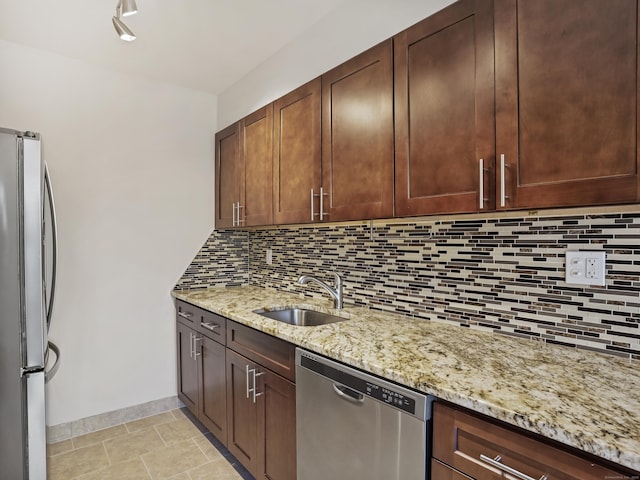 kitchen with sink, tasteful backsplash, light stone counters, light tile patterned floors, and appliances with stainless steel finishes