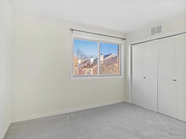 unfurnished bedroom featuring light carpet and a closet