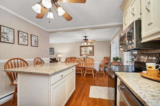 kitchen with a baseboard heating unit, dark hardwood / wood-style floors, light stone countertops, appliances with stainless steel finishes, and a breakfast bar area