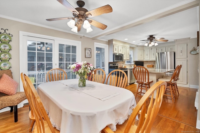 dining area featuring ceiling fan, light wood-type flooring, ornamental molding, and sink