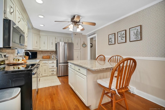 kitchen with a center island, stainless steel appliances, a kitchen breakfast bar, light hardwood / wood-style flooring, and crown molding