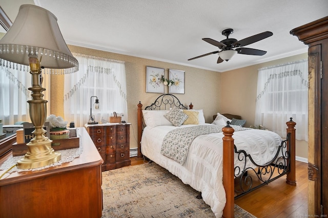 bedroom featuring hardwood / wood-style floors, ceiling fan, crown molding, and multiple windows