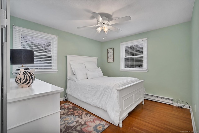 bedroom with hardwood / wood-style floors, ceiling fan, baseboard heating, and a textured ceiling