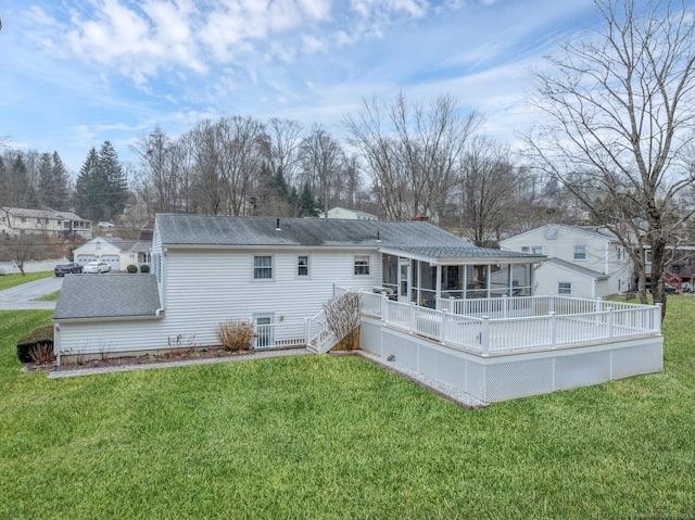 rear view of property featuring a sunroom, a deck, and a lawn