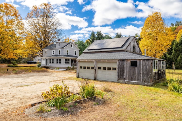 view of front of property with a garage, a front lawn, an outbuilding, and solar panels