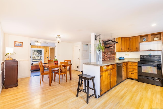 kitchen with a kitchen breakfast bar, light wood-type flooring, ceiling fan, black range with electric cooktop, and stainless steel dishwasher