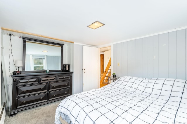 carpeted bedroom featuring wooden walls and crown molding