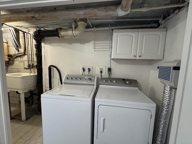 laundry area featuring cabinets, independent washer and dryer, light hardwood / wood-style flooring, and sink